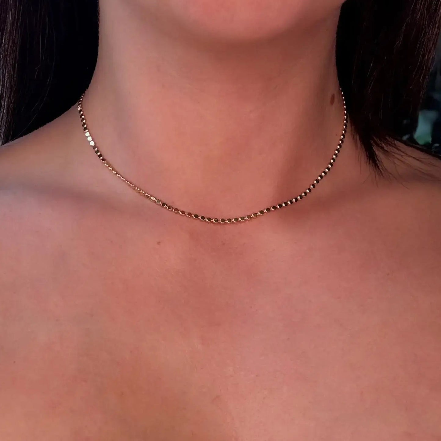 gold choker Necklace on a person with a white top