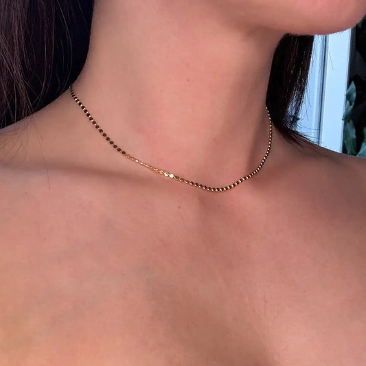gold choker Necklace on a person with a white top