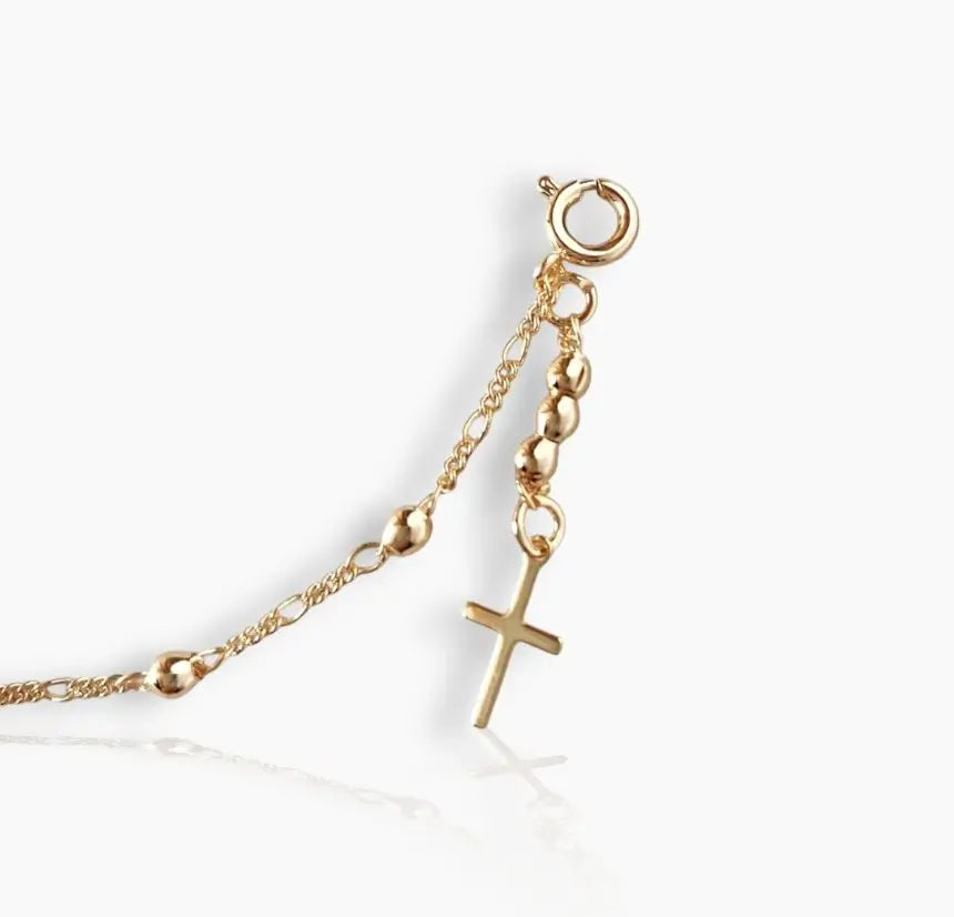 Gold bracelet with a cross charm on a white background