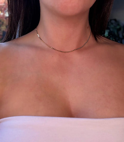 gold choker Necklace on a person with a white top