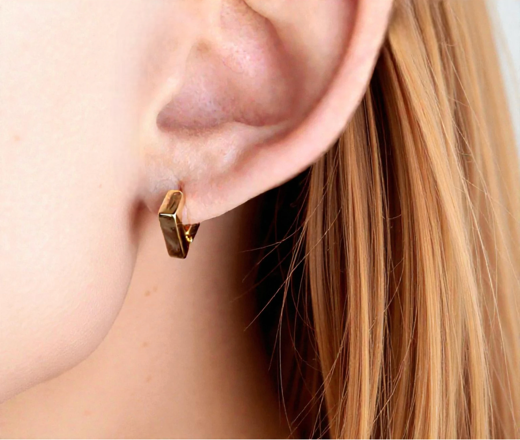 Gold hoop earring worn by a person with blonde hair.