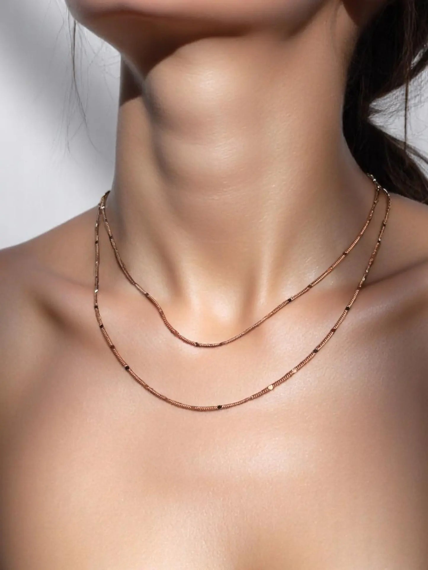 A close-up image of a woman's neck wearing a gold-filled curb chain necklace with a pressed detail.