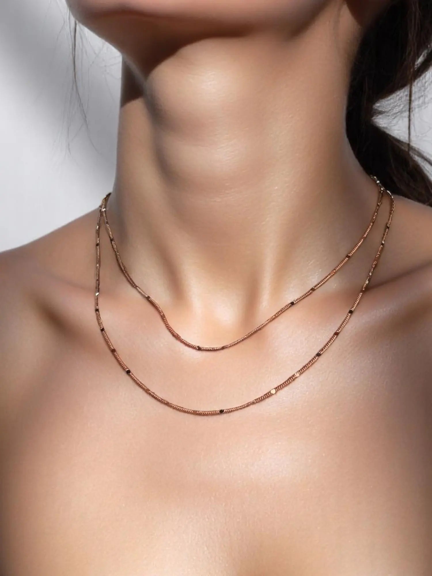A close-up image of a woman's neck wearing a gold-filled curb chain necklace with a pressed detail.