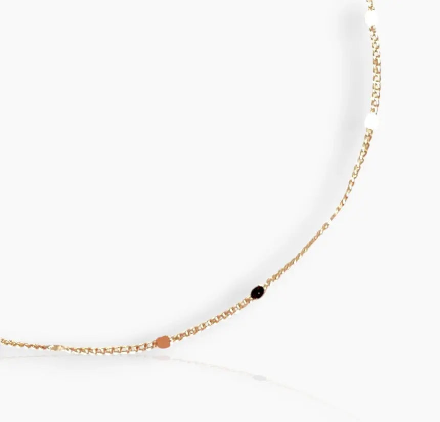 A close-up image of gold-colored bracelet with small pressed studs along the length on a white background 