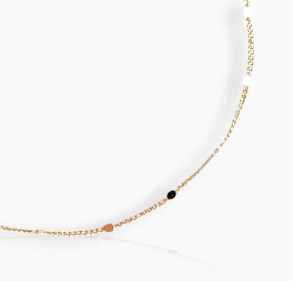 A close-up image of gold-colored bracelet with small pressed studs along the length on a white background 