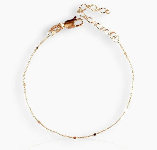 A close-up image of gold-colored bracelet with small pressed studs along the length on a white background 